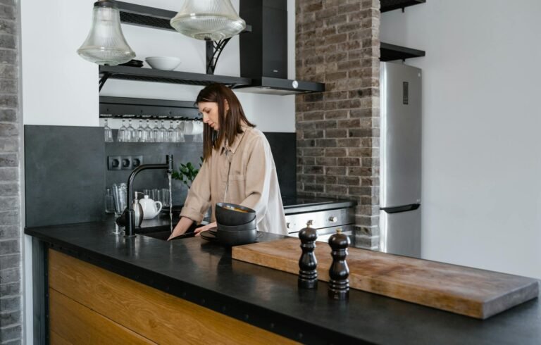 Woman in White Long Sleeve Shirt Standing in Front of Brown Wooden Table